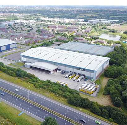 Drone shot above a warehouse, with a motorway in the foreground